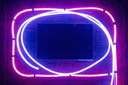 Empty blank computer screen in the neon lights on the wall background.の写真素材