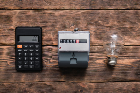 Calculator, light bulb and electric meter on the wall. Calculation of electricity costs concept.