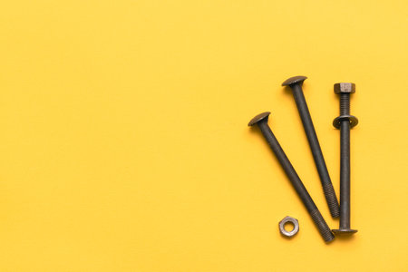Long bolts and nuts on the yellow flat lay background with copy space.の写真素材