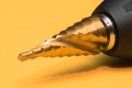 Step conical drill bit on the yellow background close up.の写真素材