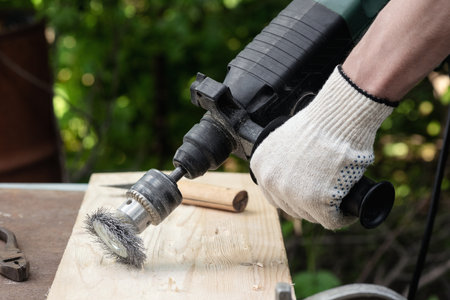 Carpenter is brushing wood by the grinding disc close up.