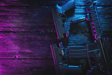 Airsoft rifle and guns on the flat lay table background with copy space. Cyberpunk weapon concept.