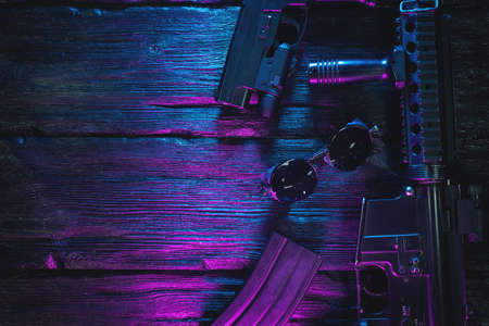 Airsoft rifle and guns on the flat lay table background with copy space. Cyberpunk weapon concept.