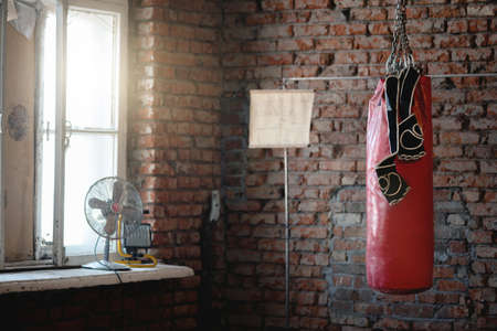 Old punching bag and boxing gloves on the brick wall background.の写真素材