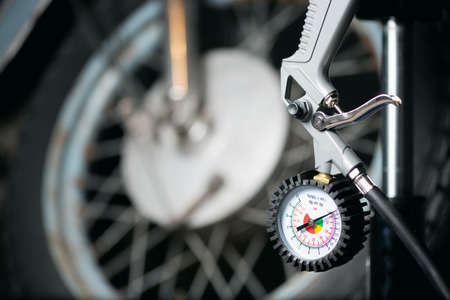 A motorbike wheel and car tyre inflation gun on the floor.の写真素材