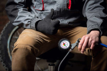 Tire fitting service worker with a car tyre inflation gun is showing a thumbs up gesture.