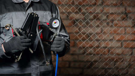 Tire fitting service worker with a car tyre inflation gun and car jack close up.の写真素材