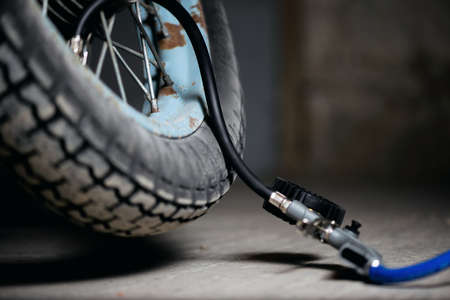 A motorbike wheel and car tyre inflation gun on the floor.の写真素材