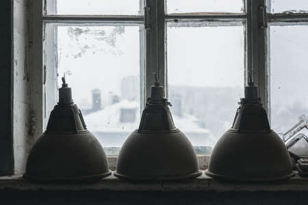 Old industrial ceiling lamps on the window sill close up background.の写真素材