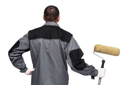 House painter with a paint roller in hand is standing on the white wall background.の写真素材