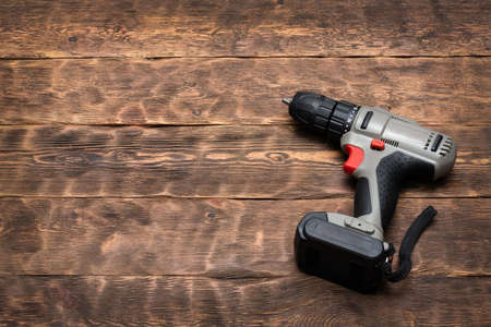 Cordless screwdriver on the wooden workbench background with copy space.