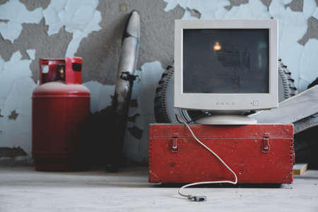 Old blank screen computer monitor with copy space on the red wooden box on the old garage background.の写真素材