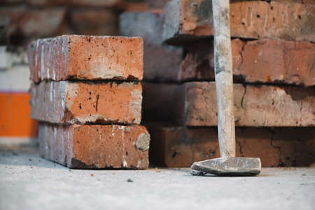 Stack of old bricks and hammer on the brick wall background.の写真素材