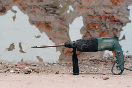 Hammer drill with chisel on the old brick wall background. Removing an old putty from the wall background.の写真素材