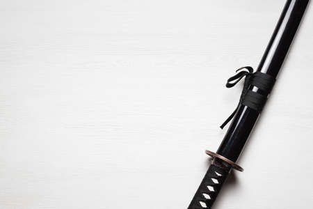 Katana sword on the white wooden table background with copy space.