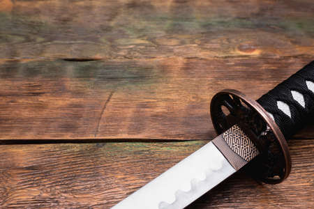 Katana sword close up on the brown wooden table background with copy space.の写真素材