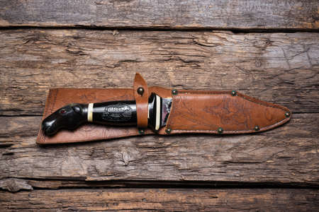 Hunting knife and leather case on the old wooden table background. Hunter accessory concept background.の写真素材