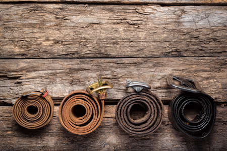 Old retro style male belts on the wooden table flat lay background with copy space.の写真素材
