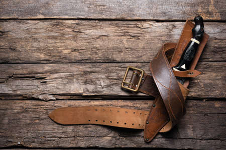 Hunting knife and leather case on the old wooden table background. Hunter accessory concept background with copy space.の写真素材