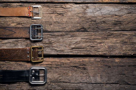 Old retro style male belts on the wooden table flat lay background with copy space.の写真素材
