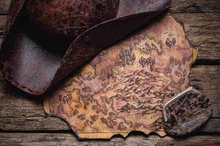 A pirate tricorn hat and treasure map on the old wooden table background.の写真素材