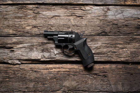 Retro style airsoft handgun on the old wooden table background.の写真素材