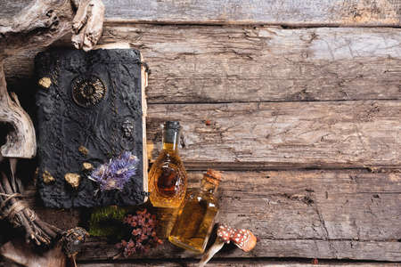 Witchcraft concept background with copy space. Witch doctor. Spell book, magic potions and dried plant on the wooden table.の写真素材