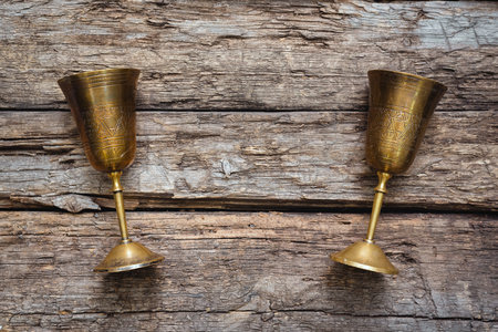 Golden goblets on the old wooden table background. Royal drink concept.の写真素材