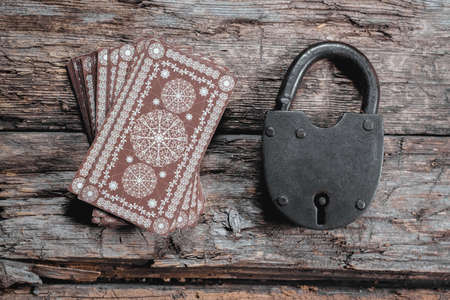Tarot cards and old padlock on the wooden table background. Hidden future.
