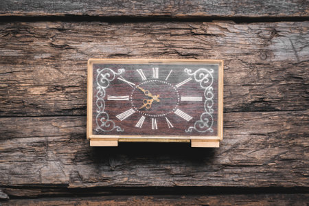 An old retro style alarm clock on the wooden table flatlay background.