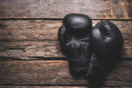 Old black boxing gloves on the wooden board flat lay background with copy space.の写真素材