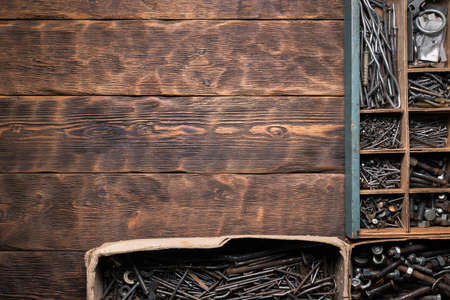 Rusty nails, nuts and bolts in the storage boxes on the old ooden carpenter workbench flat lay background.の写真素材