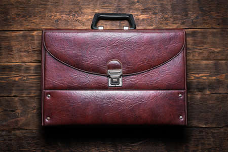 Retro style briefcase on the wooden desk table flat lay background.の写真素材