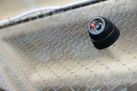 A security camera on the metal fence close up abstract background.