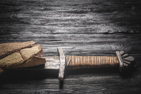 Ancient sword wrapped in the beast skin on the wooden black table flat lay background with copy space.の写真素材