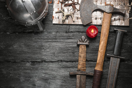 Ancient weapon, swords and ax on the black wooden table background close up.の写真素材