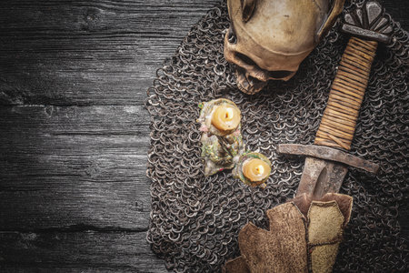 Ancient sword wrapped in the beast skin and chain mail on the wooden black table flat lay background with copy space.の写真素材