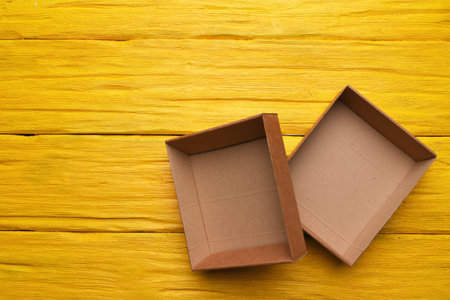 Open empty cardboard boxes on the yellow wooden flat lay desk table background.の写真素材