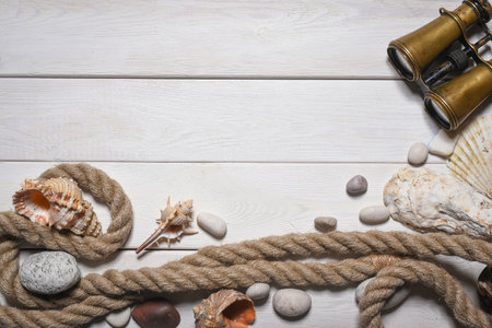 Vintage compass, binoculars, seashells and pebble stones on the white wooden desk table close up background with copy space.の写真素材