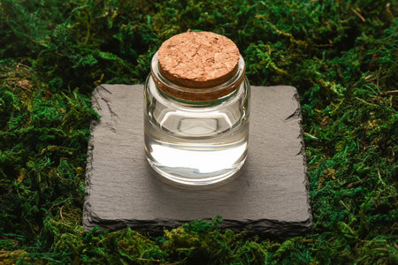 Spring water in the jar on the natural moss background.
