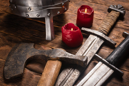 Ancient battle swords, ax and armor helmet on the wooden table background close up.の写真素材