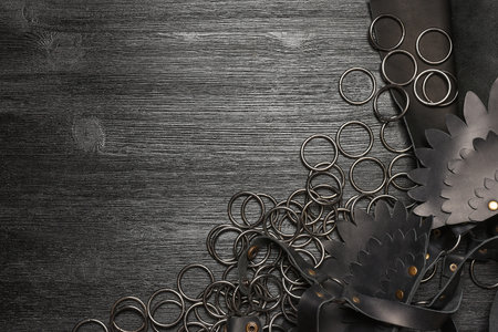 Leather piece and metal rings furniture on the wooden black table background. Leather craft concept. Top view.の写真素材