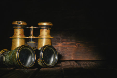 Retro binoculars on the old wooden desk table background front view close up. Travel background with copy space.の写真素材