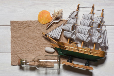 Message scroll letter in the bottle and blank crumpled blank paper sheet with copy space on the white wooden desk table flat lay background. Ancient pirate map concept.の写真素材