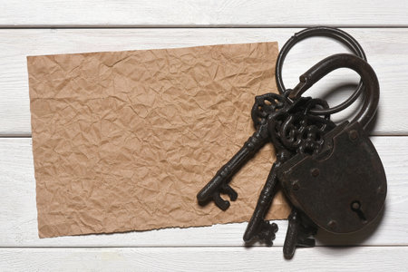 Blank crumpled paper page and old barn padlock on the wooden flat lay desk table background with copy space. Secret information concept. Looking for the answers. Searching of clues concept.の写真素材