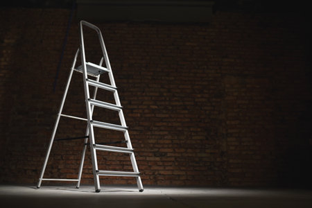 Metal stepladder on dark background with copy space.