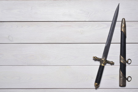 Vintage retro style dagger sword on the white wooden table background with copy space. Pirate table.の写真素材