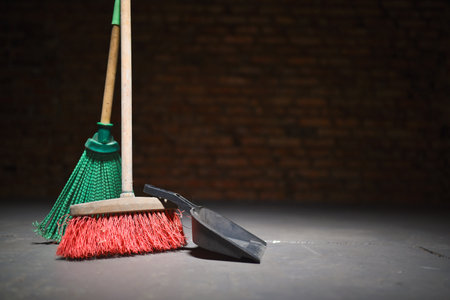 Broom and dust pan on the dirty dusty floor. Cleaning concept.
