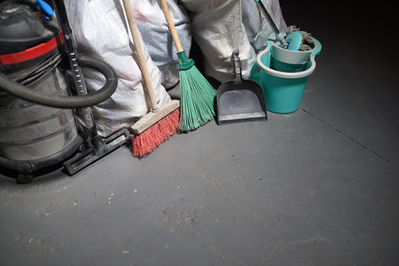 Broom, dust pan, bucket, mop, vacuum cleaner and trash bags garbage on the dirty dusty floor. Cleaning concept.の写真素材