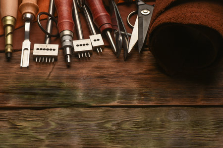 Leather craft work tools and leather on the tanner workbench concept background.